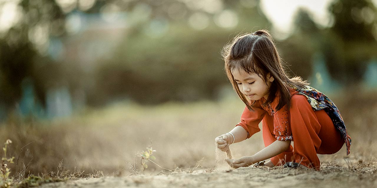 jeune fille jouant avec de la terre dans un champ